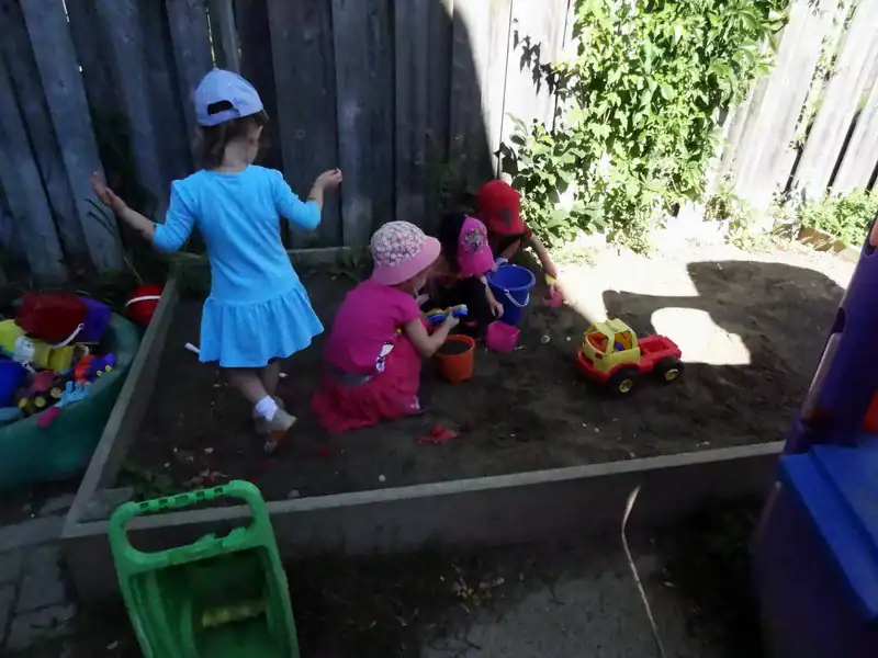 Gallery 1 Children's outdoor play area with sandbox, toys, and gardening fun at Diana Daycare.