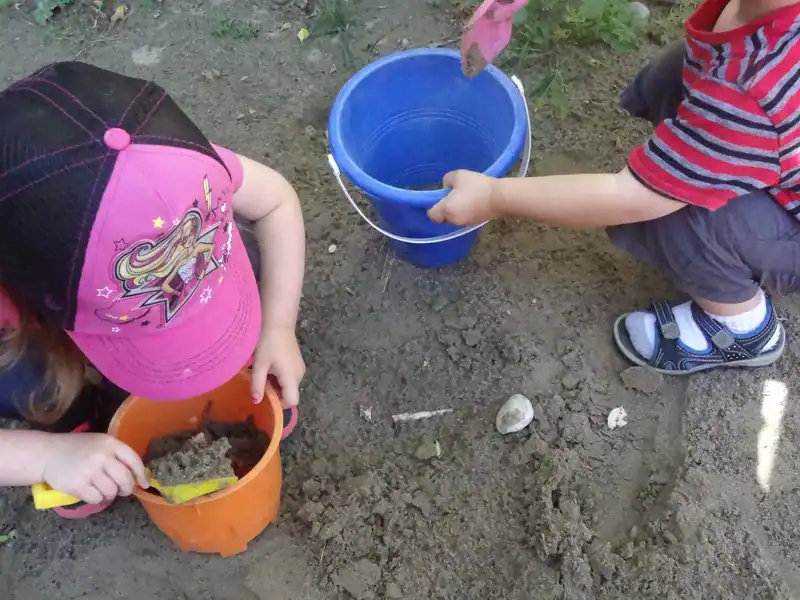 Gallery 5 Children engaging in outdoor play with sand and water during daycare activities.